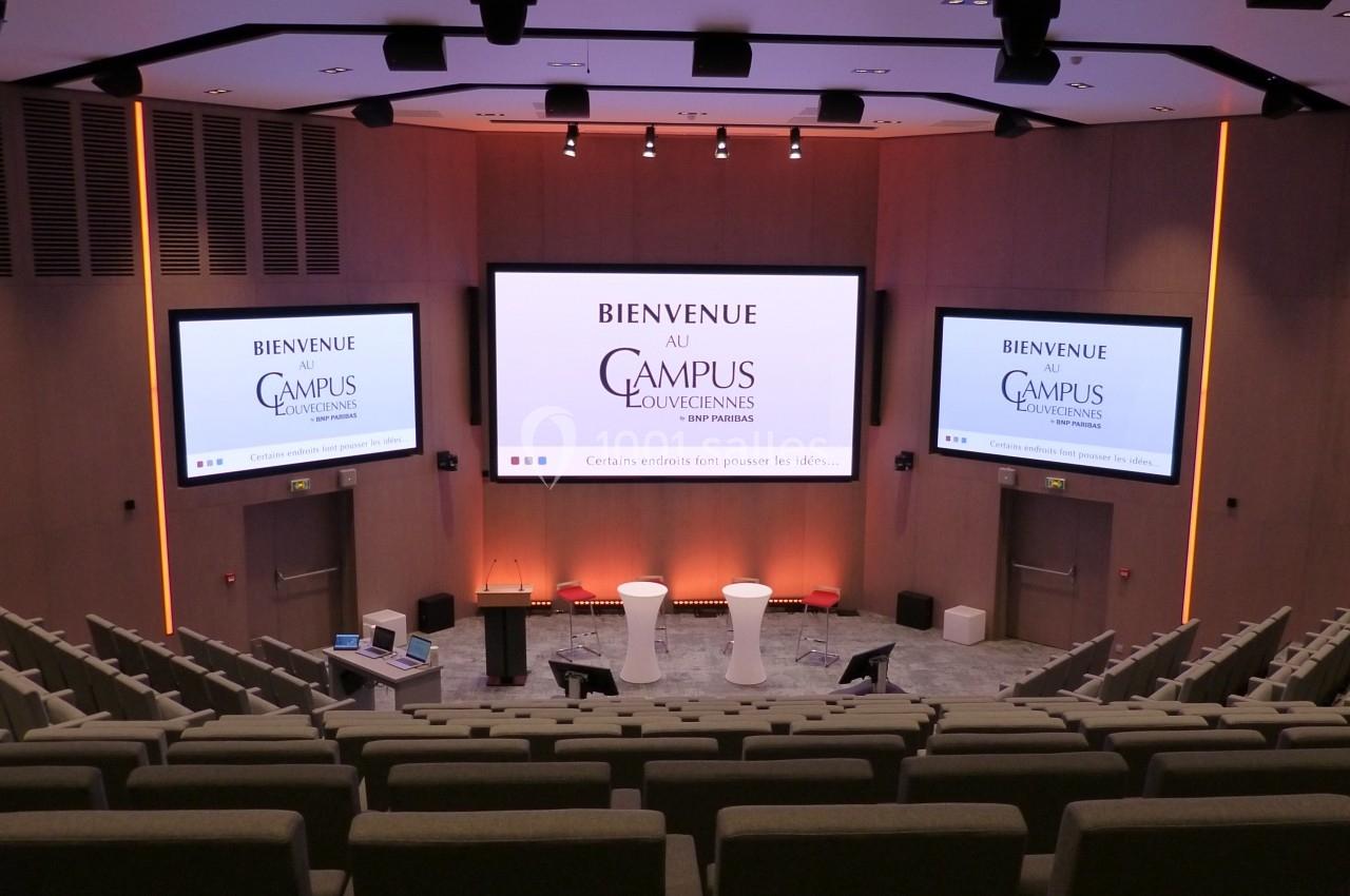 Location salle Louveciennes (Yvelines) - Campus BNP Paribas Louveciennes #6 Salle de conférence moderne avec sièges en gradins, écrans affichant ’Bienvenue au Campus Louvainensis’.