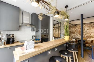 Miniature Location salle Paris 11 (Paris) - Les Rendez-vous #3 Salle de réunion moderne avec table noire, chaises, écran de projection, paperboard et cuisine ouverte en arrière-plan.