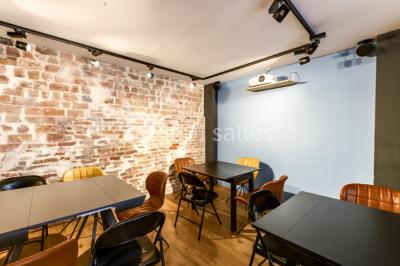 Miniature Location salle Paris 11 (Paris) - Les Rendez-vous #11 Salle de réunion moderne avec table noire, chaises, écran de projection, paperboard et cuisine ouverte en arrière-plan.