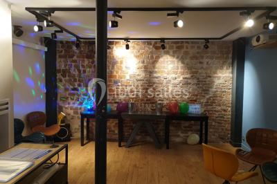 Miniature Location salle Paris 11 (Paris) - Les Rendez-vous #2 Salle de réunion moderne avec table noire, chaises, écran de projection, paperboard et cuisine ouverte en arrière-plan.