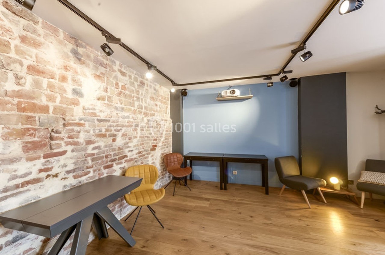 Location salle Paris 11 (Paris) - Les Rendez-vous #3 Salle lumineuse avec murs en briques et peinture bleue, parquet en bois, mobilier moderne et projecteur au plafond.