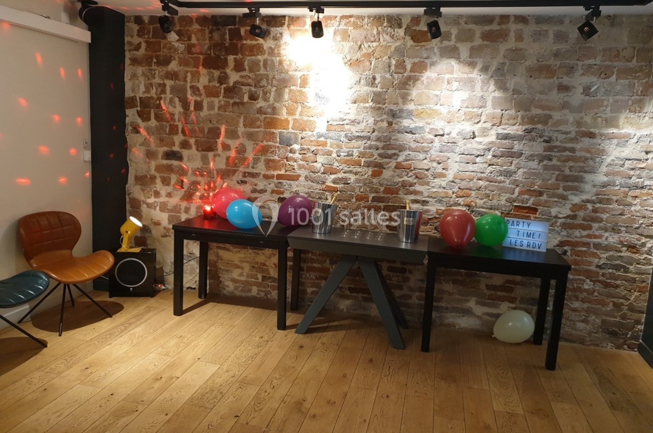 Location salle Paris 11 (Paris) - Les Rendez-vous #9 Salle décorée pour une fête avec des ballons colorés sur une table devant un mur en briques.