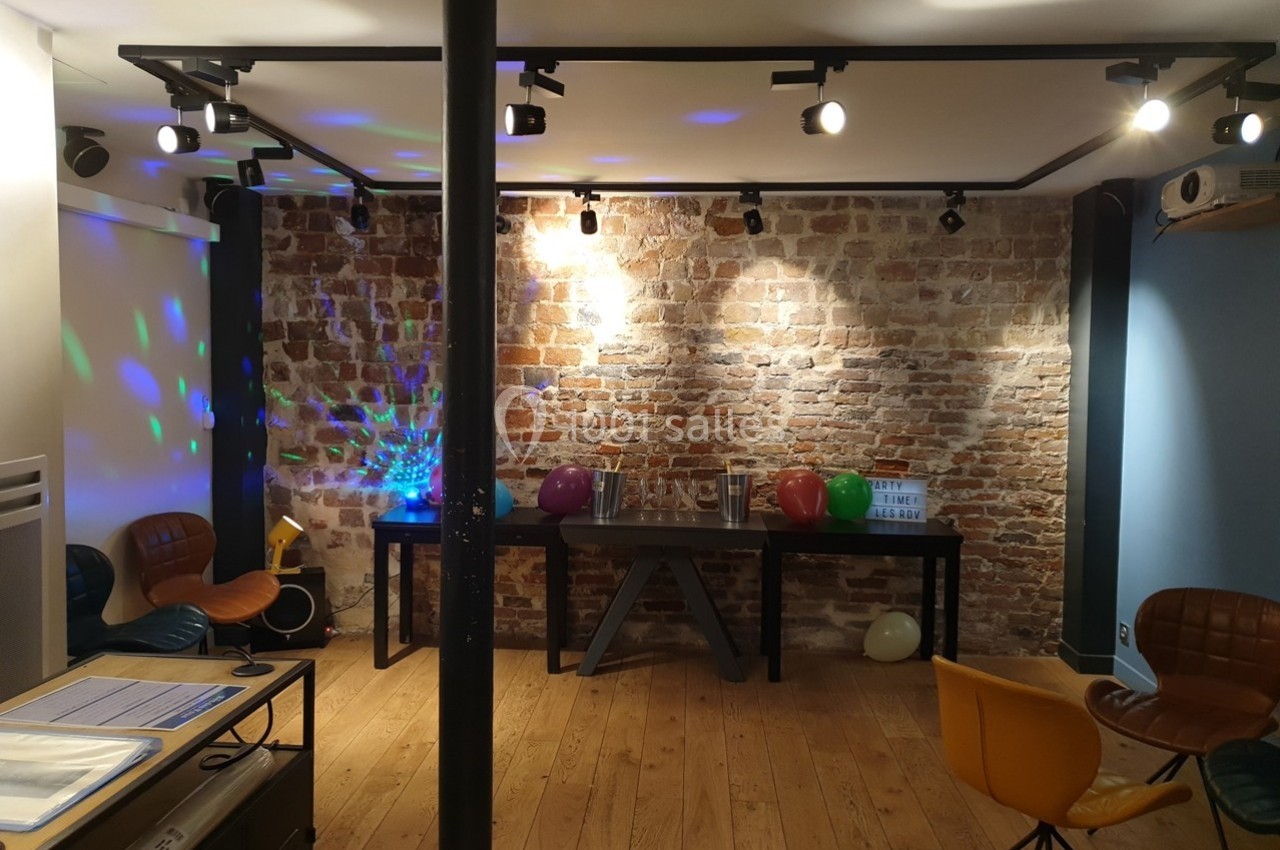 Location salle Paris 11 (Paris) - Les Rendez-vous #2 Salle avec mur en briques, parquet, chaises colorées, ballons et éclairage décoratif.