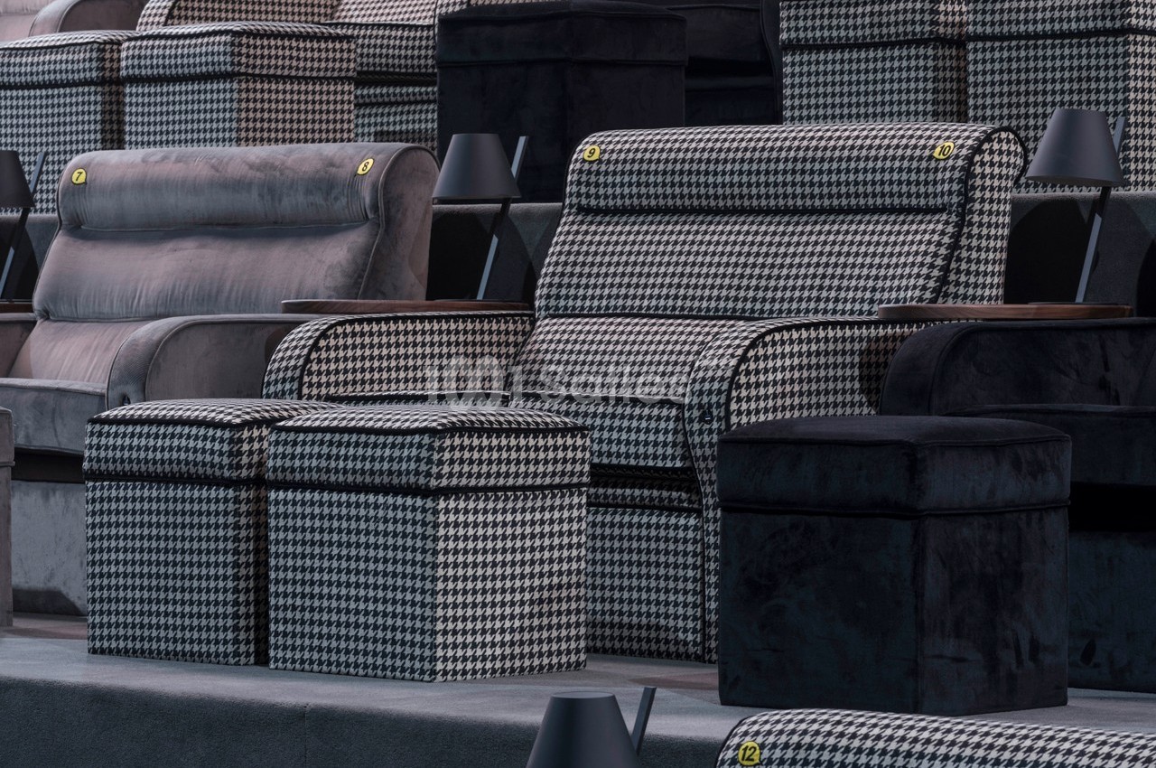 Sièges de cinéma en tissu à motif pied-de-poule avec repose-pieds assortis et accoudoirs en bois.