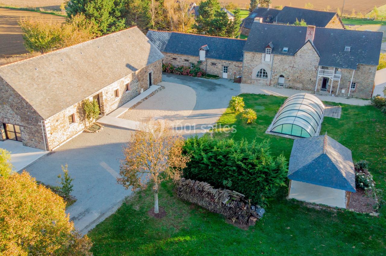 Vue aérienne d'un domaine rural avec bâtiments en pierre, cour centrale, jardin et petite serre couverte.