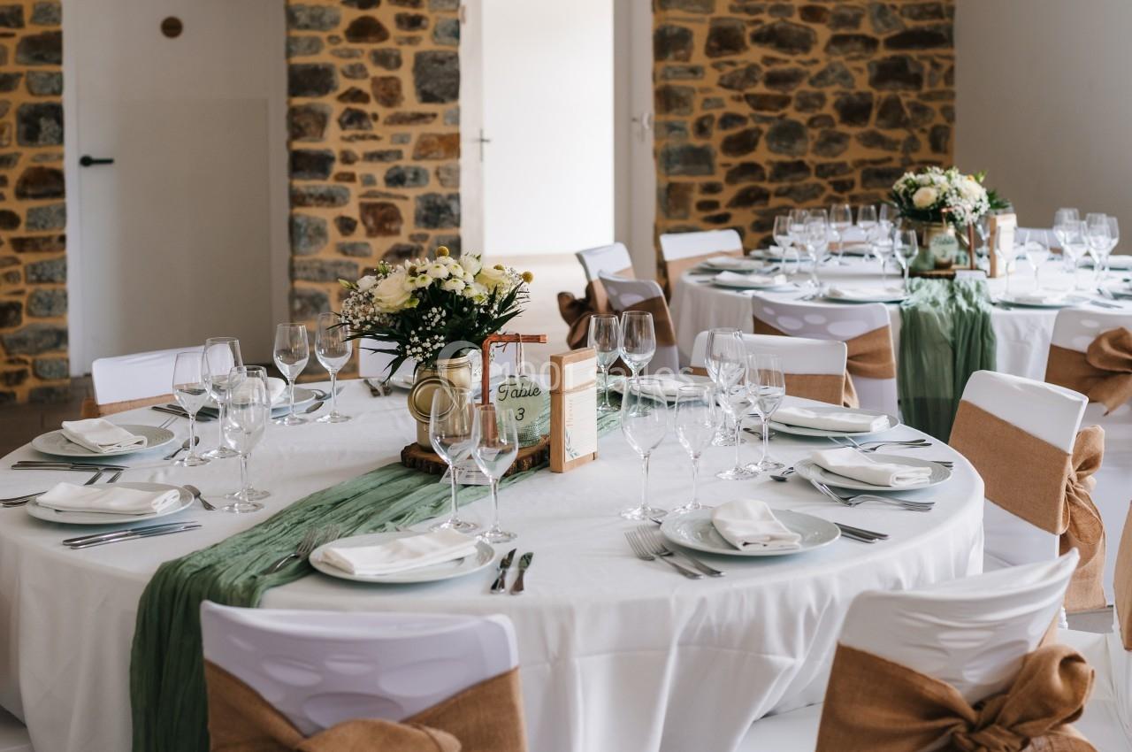 Location salle Domagné (Ille-et-Vilaine) - Domaine de Neuville #7 Salle décorée pour un événement avec tables rondes dressées, nappes blanches, chemins de table verts et chaises ornées de…