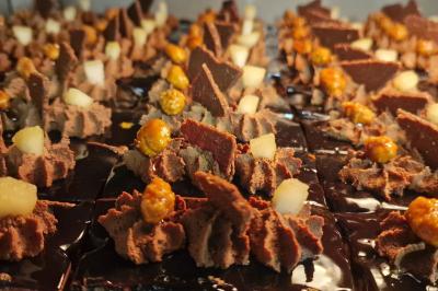 Miniature Location salle Domagné (Ille-et-Vilaine) - Domaine de Neuville #18 Assiette contenant des cookies et un petit gâteau sur une table noire, avec des verres et un vase décoratif à proximité.