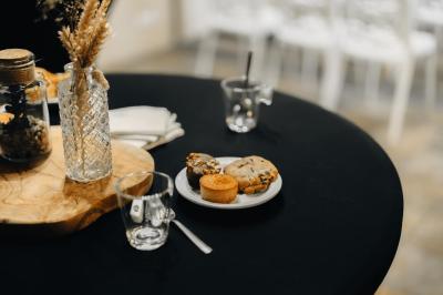 Miniature Location salle Domagné (Ille-et-Vilaine) - Domaine de Neuville #20 Assiette contenant des cookies et un petit gâteau sur une table noire, avec des verres et un vase décoratif à proximité.