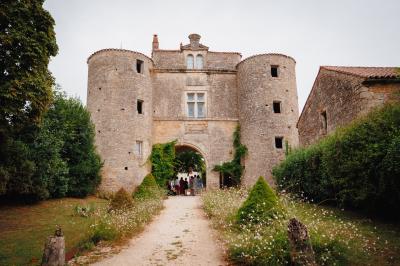 Miniature Location salle Cezais (Vendée) - Château de la Cressonnière #12 Un homme debout, bras ouverts, s'exprime devant un mur en pierre, avec une chaise en bois à côté de lui.