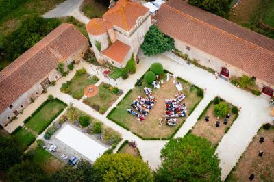 Miniature Location salle Cezais (Vendée) - Château de la Cressonnière #13 Un homme debout, bras ouverts, s'exprime devant un mur en pierre, avec une chaise en bois à côté de lui.