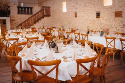 Miniature Location salle Cezais (Vendée) - Château de la Cressonnière #35 Un homme debout, bras ouverts, s'exprime devant un mur en pierre, avec une chaise en bois à côté de lui.
