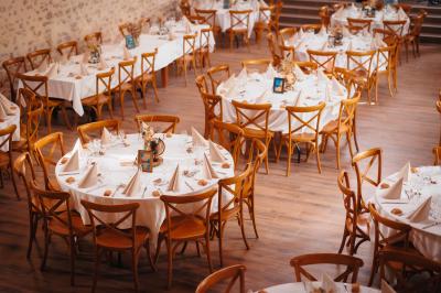 Miniature Location salle Cezais (Vendée) - Château de la Cressonnière #33 Un homme debout, bras ouverts, s'exprime devant un mur en pierre, avec une chaise en bois à côté de lui.