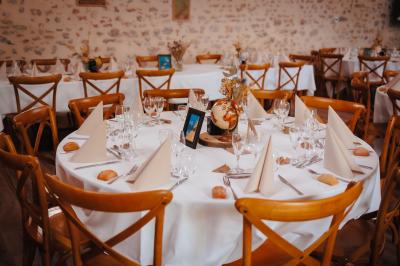 Miniature Location salle Cezais (Vendée) - Château de la Cressonnière #36 Un homme debout, bras ouverts, s'exprime devant un mur en pierre, avec une chaise en bois à côté de lui.