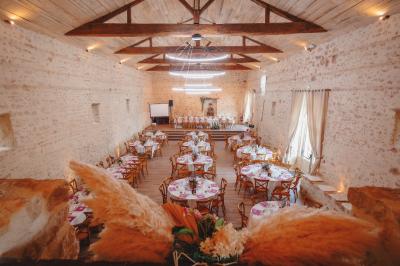 Miniature Location salle Cezais (Vendée) - Château de la Cressonnière #37 Un homme debout, bras ouverts, s'exprime devant un mur en pierre, avec une chaise en bois à côté de lui.