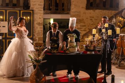 Miniature Location salle Cezais (Vendée) - Château de la Cressonnière #39 Un homme debout, bras ouverts, s'exprime devant un mur en pierre, avec une chaise en bois à côté de lui.