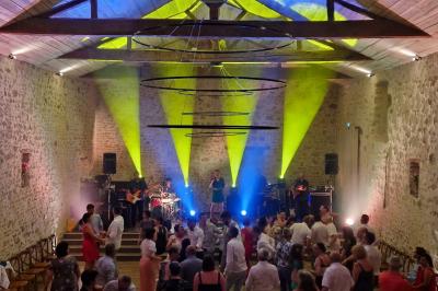 Miniature Location salle Cezais (Vendée) - Château de la Cressonnière #40 Un homme debout, bras ouverts, s'exprime devant un mur en pierre, avec une chaise en bois à côté de lui.