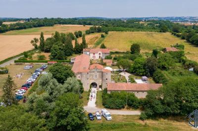 Miniature Location salle Cezais (Vendée) - Château de la Cressonnière #14 Un homme debout, bras ouverts, s'exprime devant un mur en pierre, avec une chaise en bois à côté de lui.