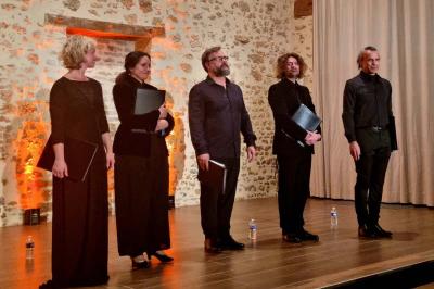 Miniature Location salle Cezais (Vendée) - Château de la Cressonnière #47 Un homme debout, bras ouverts, s'exprime devant un mur en pierre, avec une chaise en bois à côté de lui.
