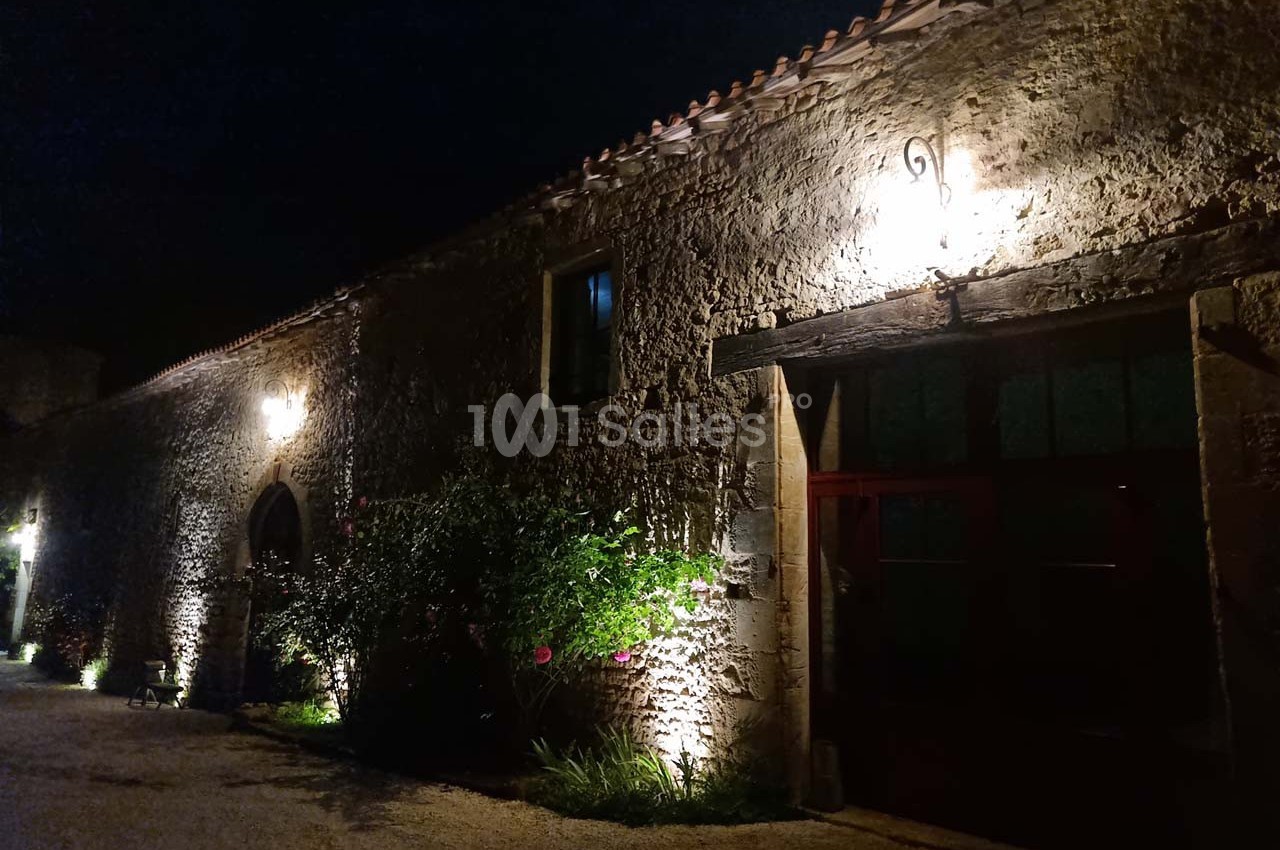 Façade en pierre d'un bâtiment ancien éclairé par des lumières extérieures la nuit.