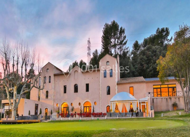 Location salle Marseille 11 (Bouches-du-Rhône) - La Bastide de la Salette #13 Bâtiment en pierre de style méditerranéen entouré d'arbres, avec une terrasse et une pelouse au premier plan.