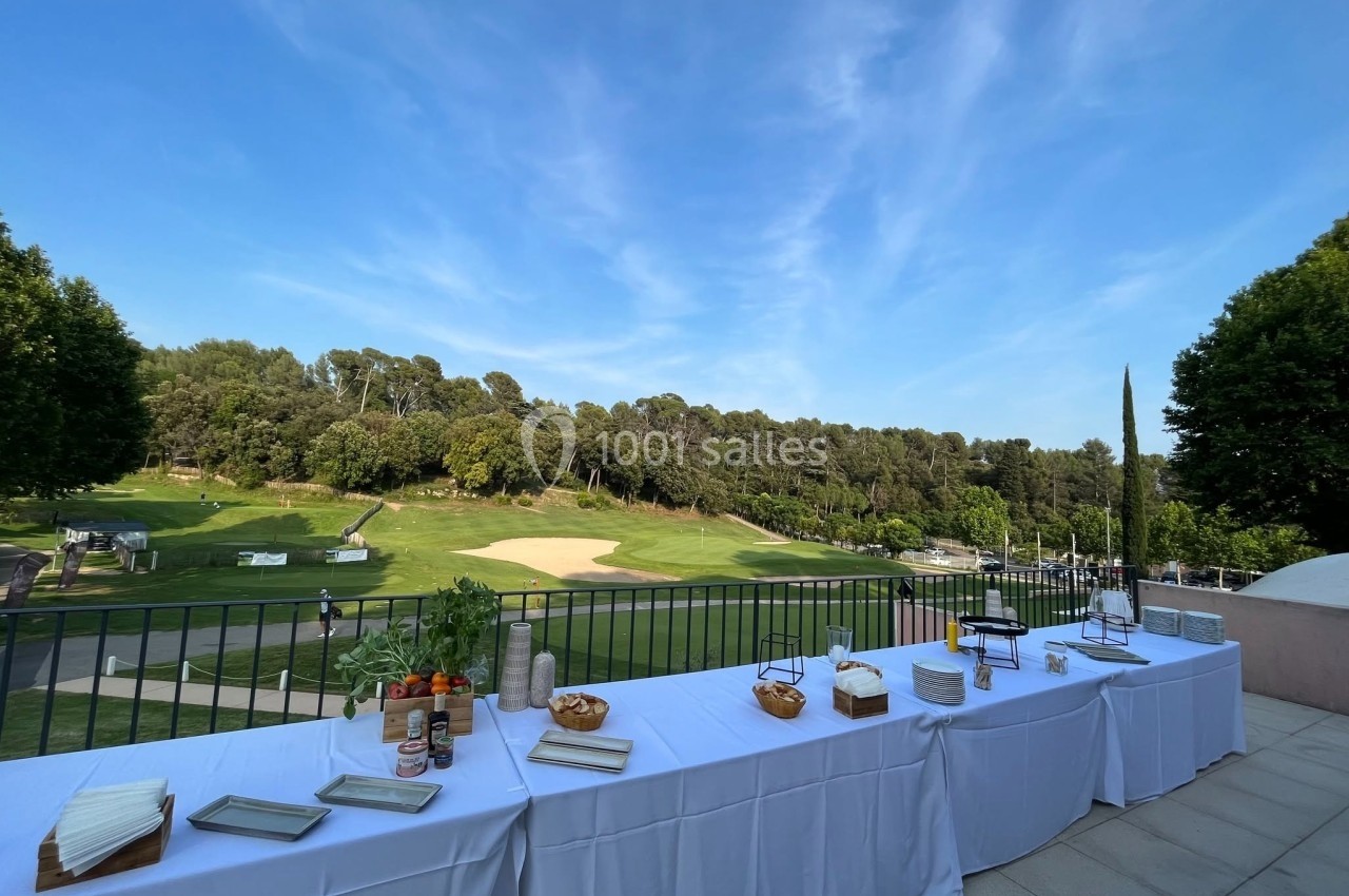 Location salle Marseille 11 (Bouches-du-Rhône) - La Bastide de la Salette #3 Tables dressées avec des plats et condiments en extérieur, donnant sur un terrain de golf entouré d'arbres.