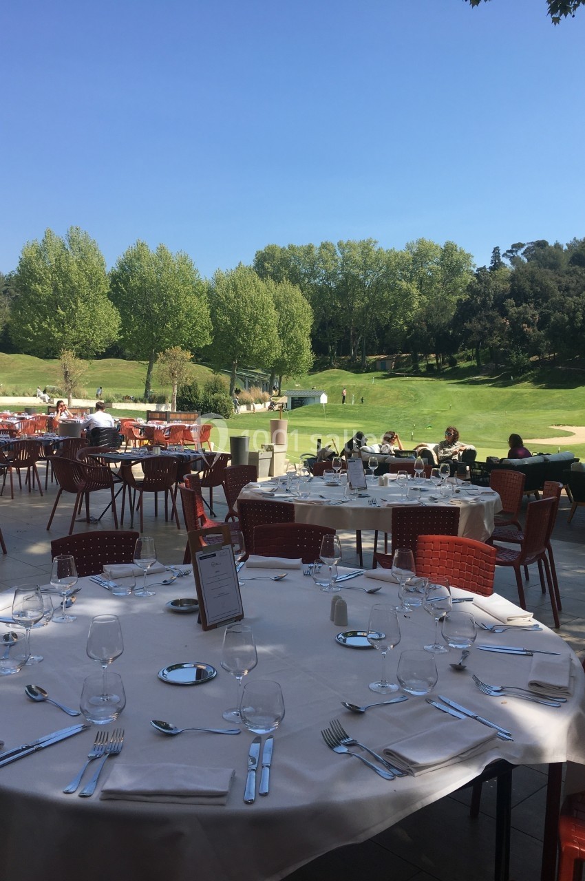 Location salle Marseille 11 (Bouches-du-Rhône) - La Bastide de la Salette #10 Terrasse d'un restaurant avec des tables dressées, vue sur un terrain de golf entouré d'arbres sous un ciel bleu.