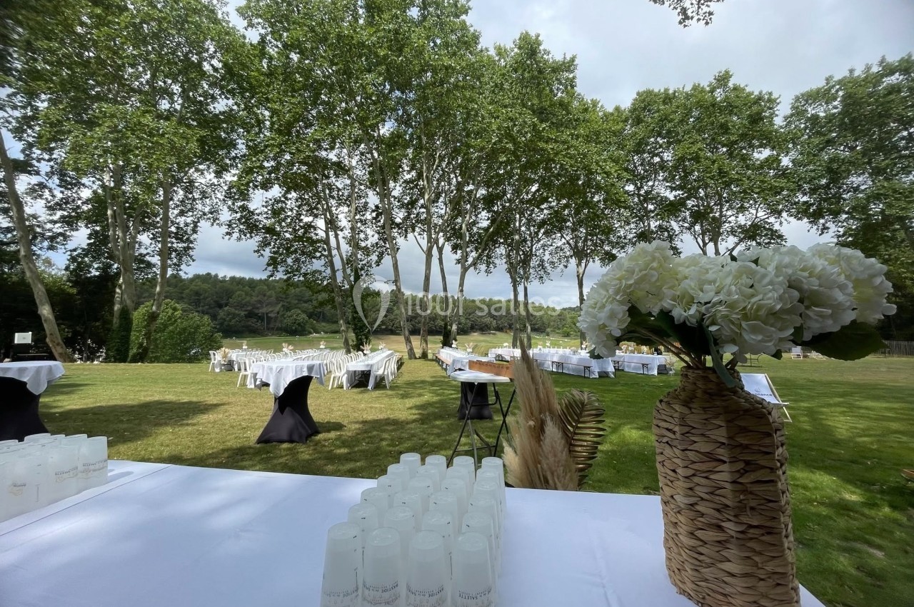 Location salle Marseille 11 (Bouches-du-Rhône) - La Bastide de la Salette #7 Tables dressées et décorations florales sur une pelouse verdoyante, entourée d'arbres et d'un paysage naturel.