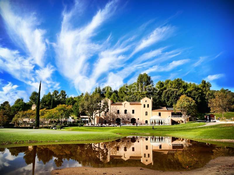 Location salle Marseille 11 (Bouches-du-Rhône) - La Bastide de la Salette #2 Bâtiment beige entouré de verdure, reflété dans un plan d'eau sous un ciel bleu avec des nuages légers.
