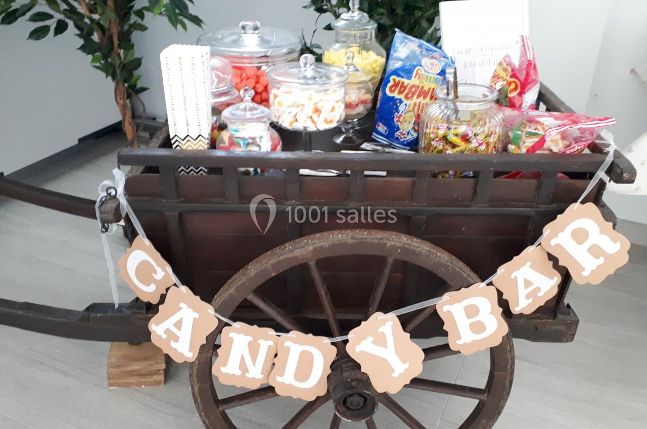 Chariot en bois décoré avec des bonbonnières remplies de sucreries et une guirlande indiquant ’Candy Bar’.