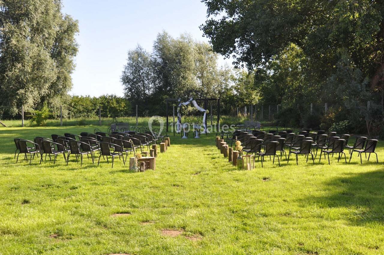 Chaises disposées en rangées sur une pelouse, face à une arche décorée pour une cérémonie en plein air.