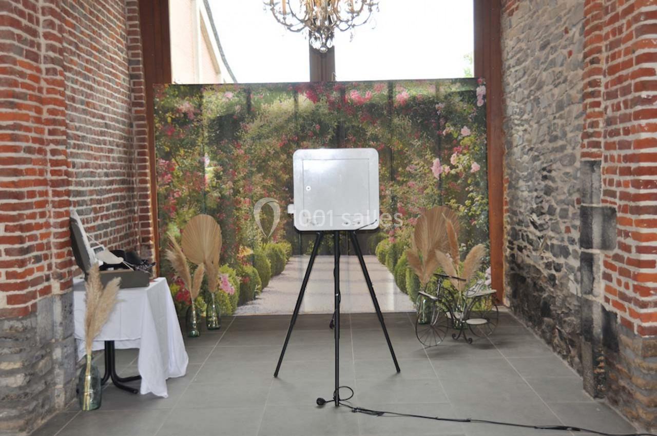 Miroir interactif sur trépied dans une salle en briques avec décor floral et éléments de décoration en pampas.