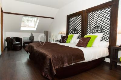 Un couple en tenue de mariage se tient sur un balcon en pierre devant une fenêtre illuminée.