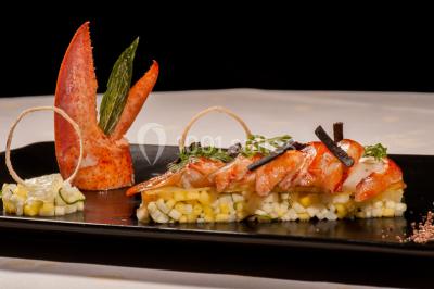 Un couple en tenue de mariage se tient sur un balcon en pierre devant une fenêtre illuminée.