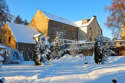 Un couple en tenue de mariage se tient sur un balcon en pierre devant une fenêtre illuminée.