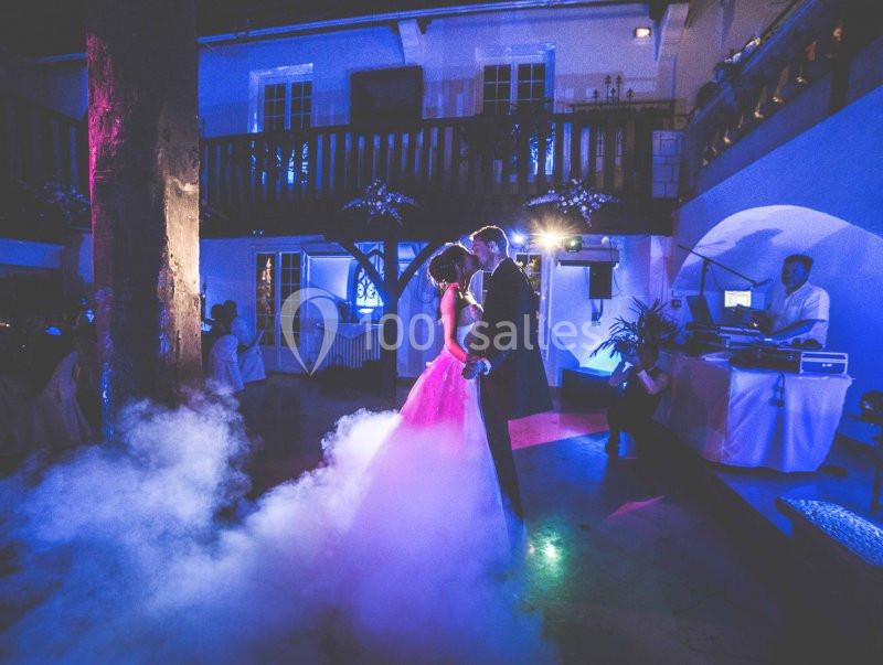 Un couple danse dans une salle éclairée de lumières colorées, entouré de fumée au sol.