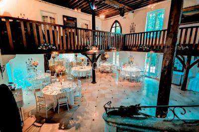 Un couple en tenue de mariage se tient sur un balcon en pierre devant une fenêtre illuminée.