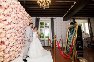 Un couple en tenue de mariage se tient sur un balcon en pierre devant une fenêtre illuminée.