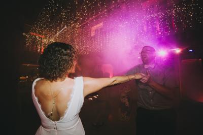 Un couple en tenue de mariage se tient sur un balcon en pierre devant une fenêtre illuminée.