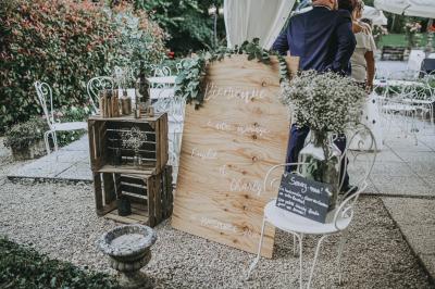 Un couple en tenue de mariage se tient sur un balcon en pierre devant une fenêtre illuminée.