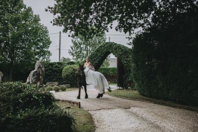 Un couple en tenue de mariage se tient sur un balcon en pierre devant une fenêtre illuminée.