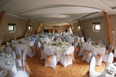 Deux tentes blanches montées sur une pelouse avec des tables et des chaises disposées autour, entourées de verdure.