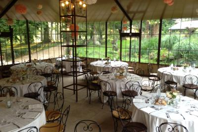 Deux tentes blanches montées sur une pelouse avec des tables et des chaises disposées autour, entourées de verdure.