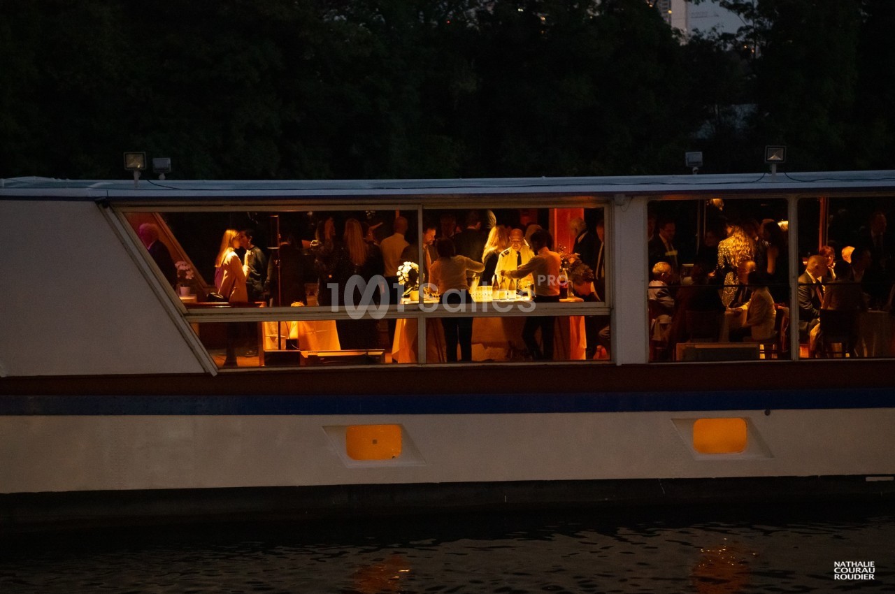 Personnes rassemblées à l'intérieur d'un bateau éclairé, partageant un moment festif en soirée.