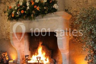 Brasero allumé dans une cour gravillonnée devant un bâtiment éclairé avec des murs en bois et des portes vitrées.