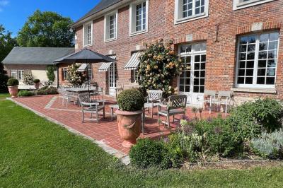 Brasero allumé dans une cour gravillonnée devant un bâtiment éclairé avec des murs en bois et des portes vitrées.