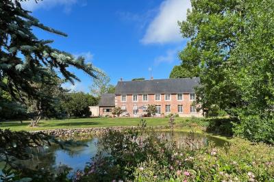 Brasero allumé dans une cour gravillonnée devant un bâtiment éclairé avec des murs en bois et des portes vitrées.