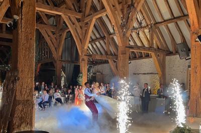 Brasero allumé dans une cour gravillonnée devant un bâtiment éclairé avec des murs en bois et des portes vitrées.