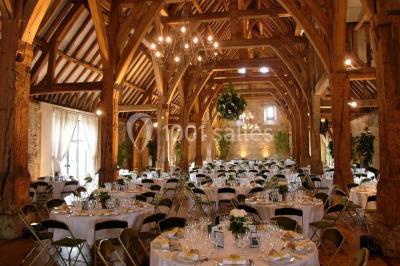 Brasero allumé dans une cour gravillonnée devant un bâtiment éclairé avec des murs en bois et des portes vitrées.