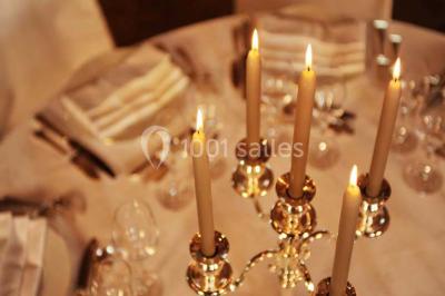 Brasero allumé dans une cour gravillonnée devant un bâtiment éclairé avec des murs en bois et des portes vitrées.