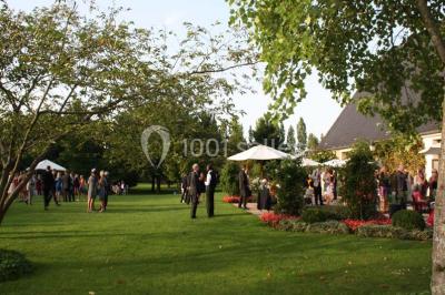 Brasero allumé dans une cour gravillonnée devant un bâtiment éclairé avec des murs en bois et des portes vitrées.